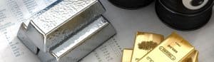 3 Goldbarren und 3 Silberbarren auf einem Schreibtisch gestapelt.